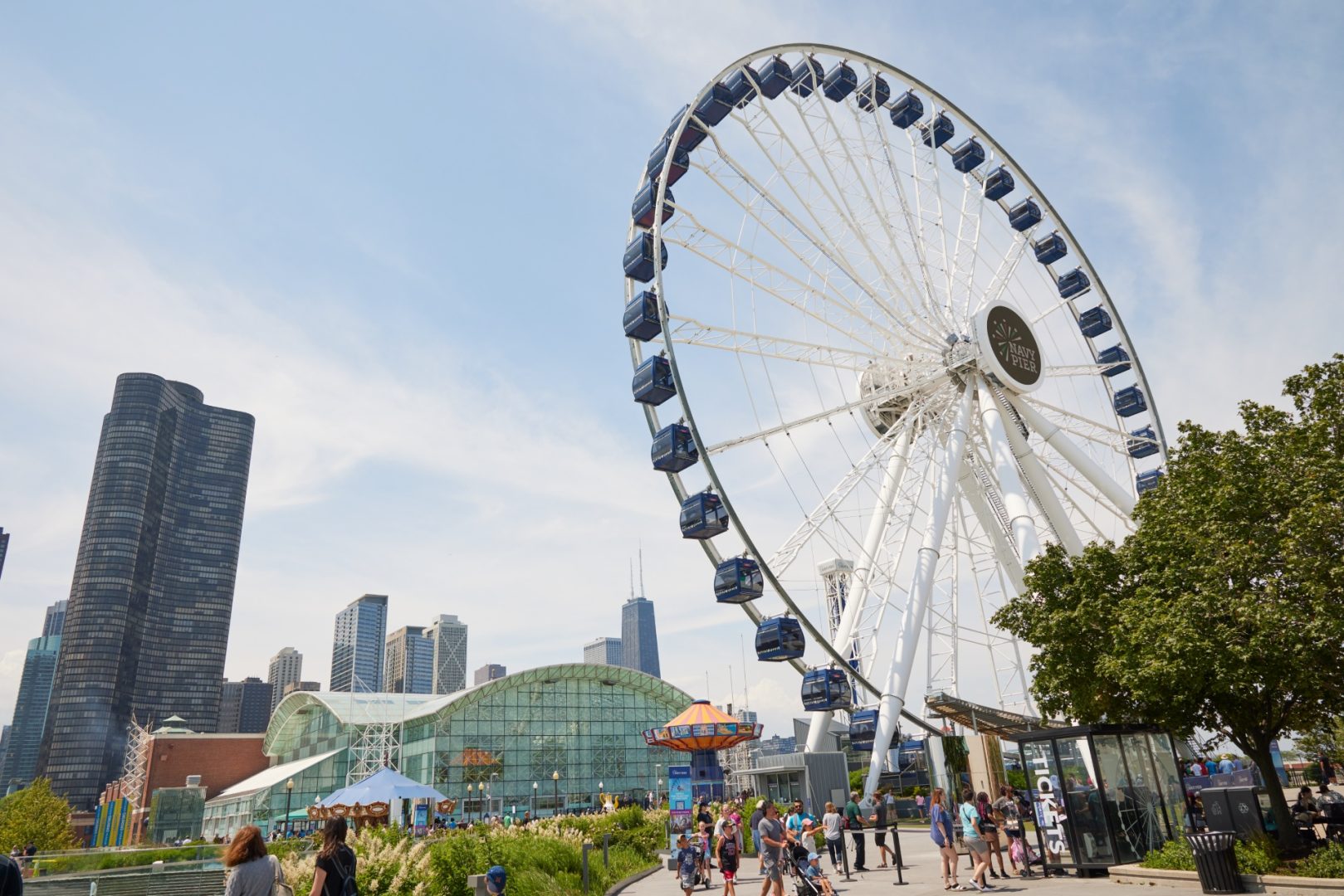 Low angle of Navy Pier's ferris wheel and attractions with the cityscape in the background.